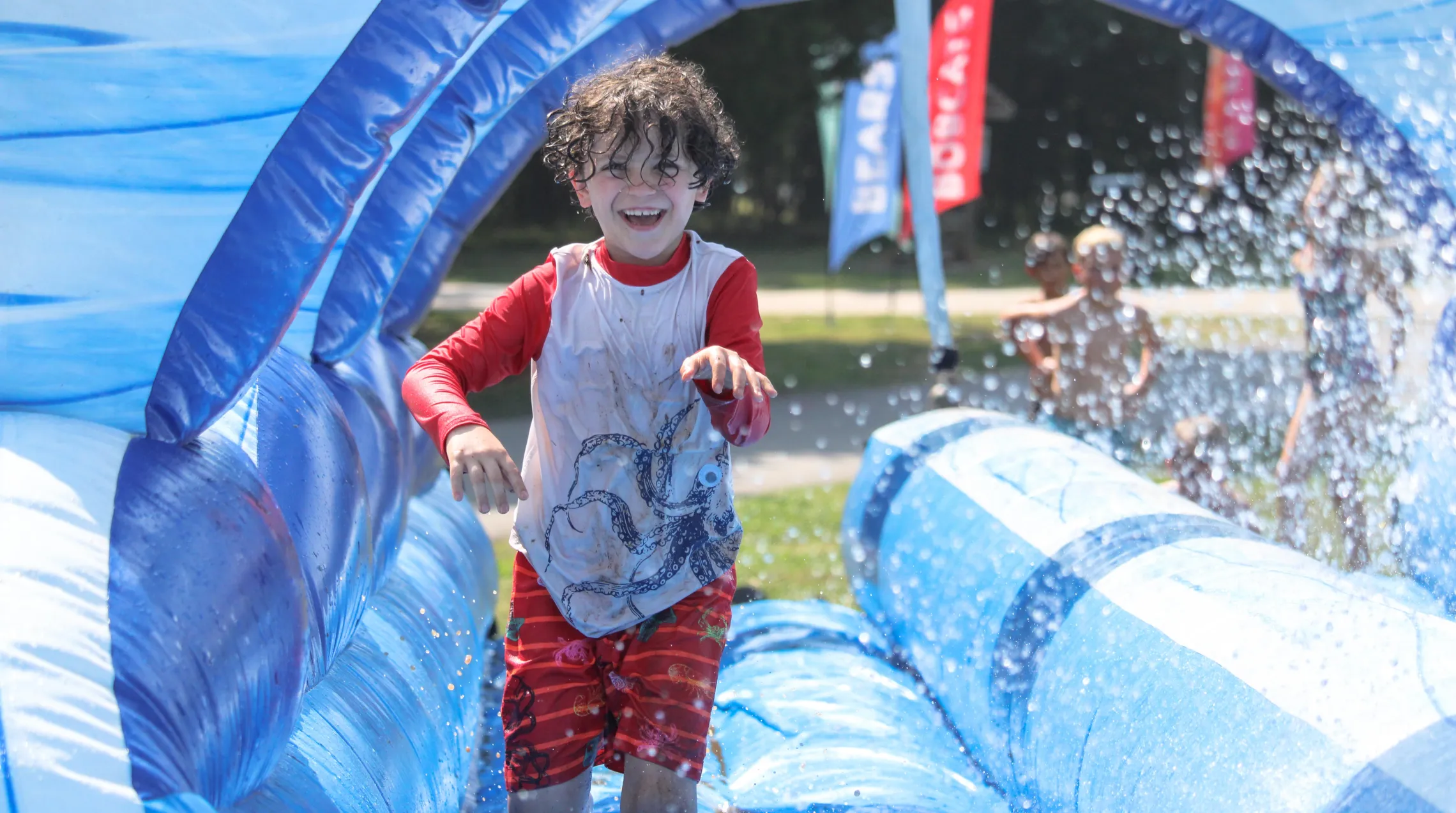 Day Camp kid running through water slide