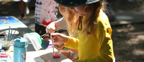 Child painting at Art explosion camp